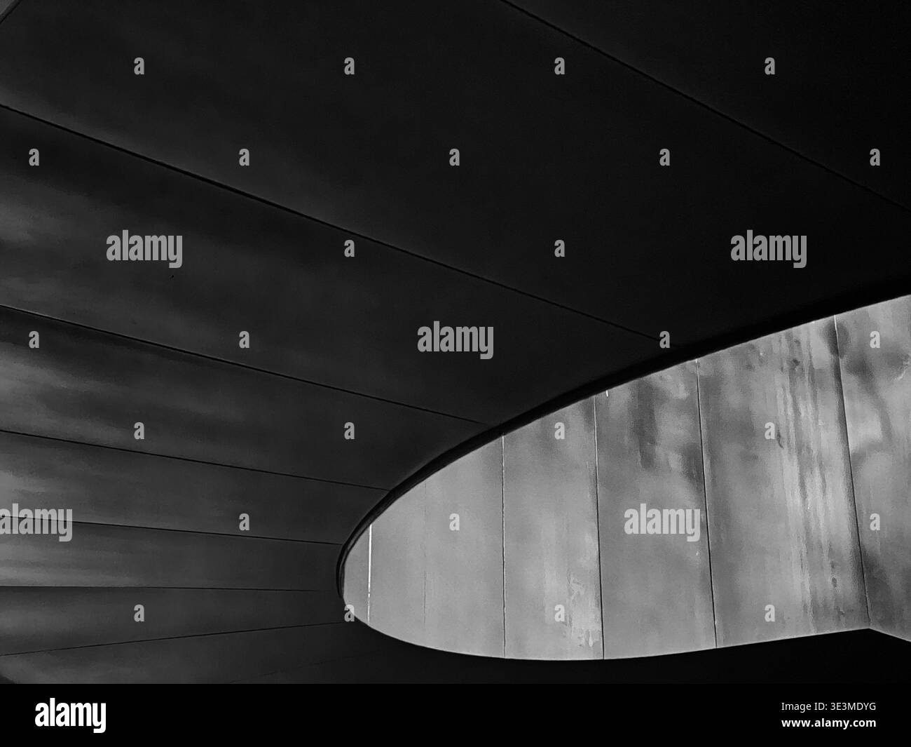 La lumière remplit le vide au centre d'un grand escalier en colimaçon dans un abstrait architectural. Banque D'Images