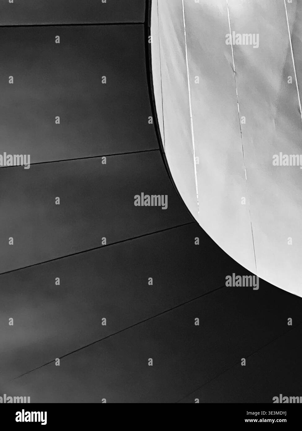 Une forme ovale, rappelant une lune, émerge du contraste de la lumière dans un abstrait architectural. Banque D'Images