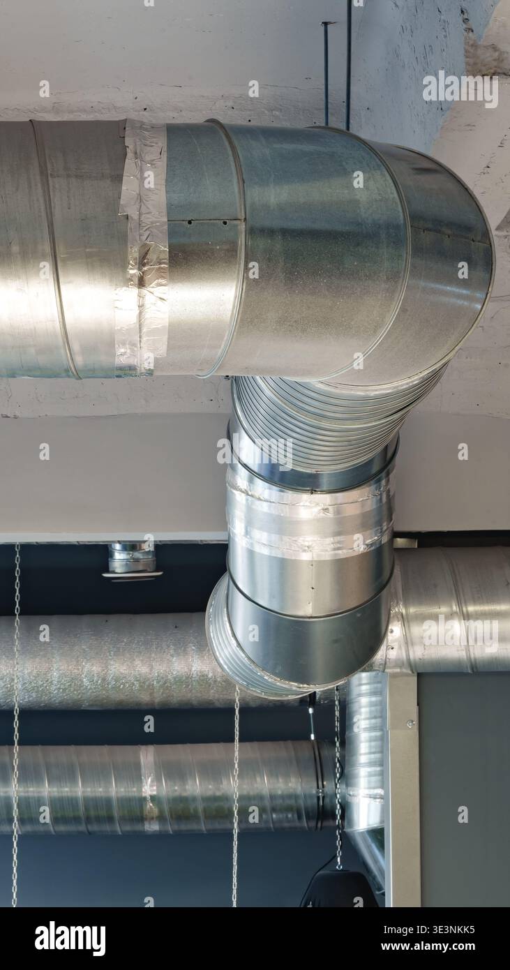 Tuyaux et conduits au plafond dans un bâtiment moderne pendant les heures de lumière du jour Banque D'Images