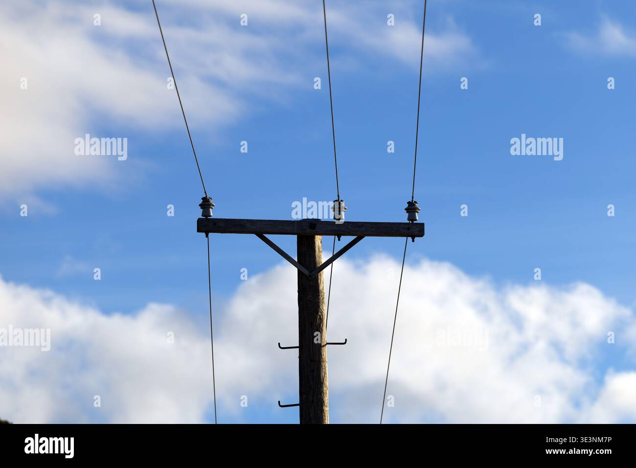 Poteau utilitaire en bois avec lignes électriques contre le ciel bleu et les nuages Banque D'Images