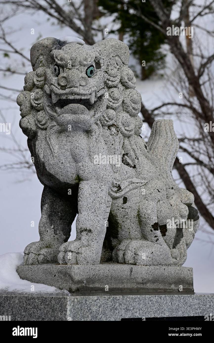 Statue d'un lion de pierre au petit sanctuaire shinto à Rausu, péninsule de Shiretoko, Hokkaido, Japon. Banque D'Images
