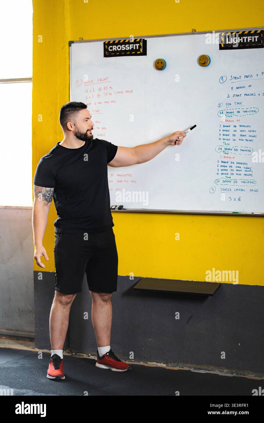 Entraîneur de fitness expliquant l'entraînement CrossFit sur le tableau blanc Banque D'Images