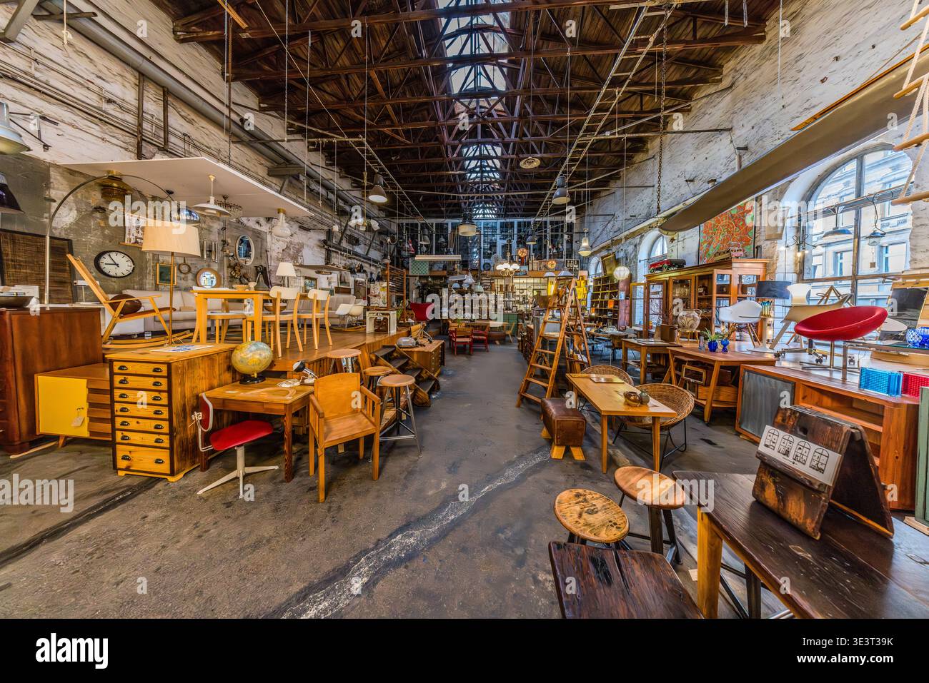 Un magasin d'antiquités installé dans un entrepôt industriel reconverti avec un toit en verre et des poutres de toit en fonte : meubles, lampes, horloges et petits objets de différentes décennies du XXe siècle, exposés côte à côte. Leipzig, Saxe, Allemagne Banque D'Images
