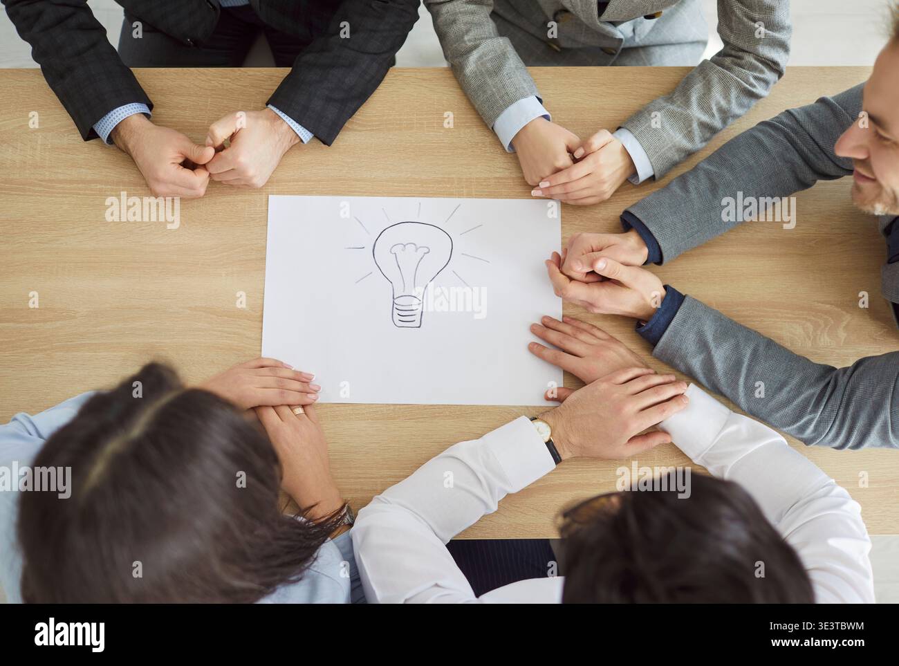 Équipe de personnes développant une nouvelle idée d'entreprise créative à table avec dessin d'ampoule Banque D'Images