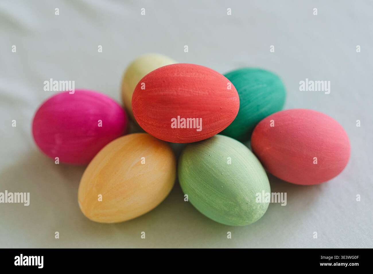 Une collection d'oeufs de Pâques multicolores vibrants exposés sur une surface de tissu doux et neutre, soulignant l'esprit festif et joyeux de l'Orient Banque D'Images