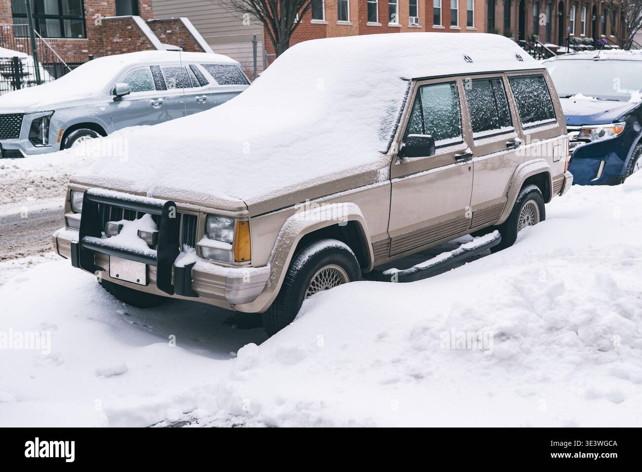 Scène urbaine de rue après une forte chute de neige, avec des voitures enterrées sous la neige et des rues bordées de couches blanches intactes. Ce paysage hivernal capture Banque D'Images