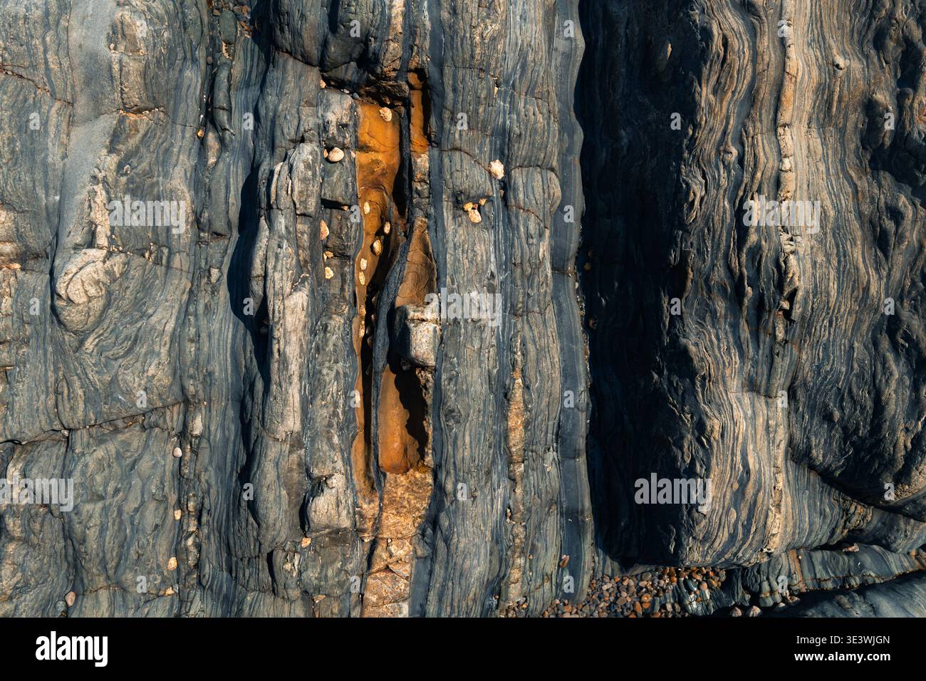 Gros plan d'une surface rocheuse accidentée présentant des formations naturelles complexes et des textures. Différentes nuances de gris et d'orange créent un g visuellement frappant Banque D'Images