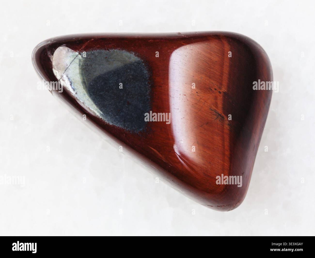 Plan macro d'un échantillon de roche naturelle de pierre précieuse en oeil de bœuf poli sur fond de marbre blanc d'Afrique du Sud Banque D'Images