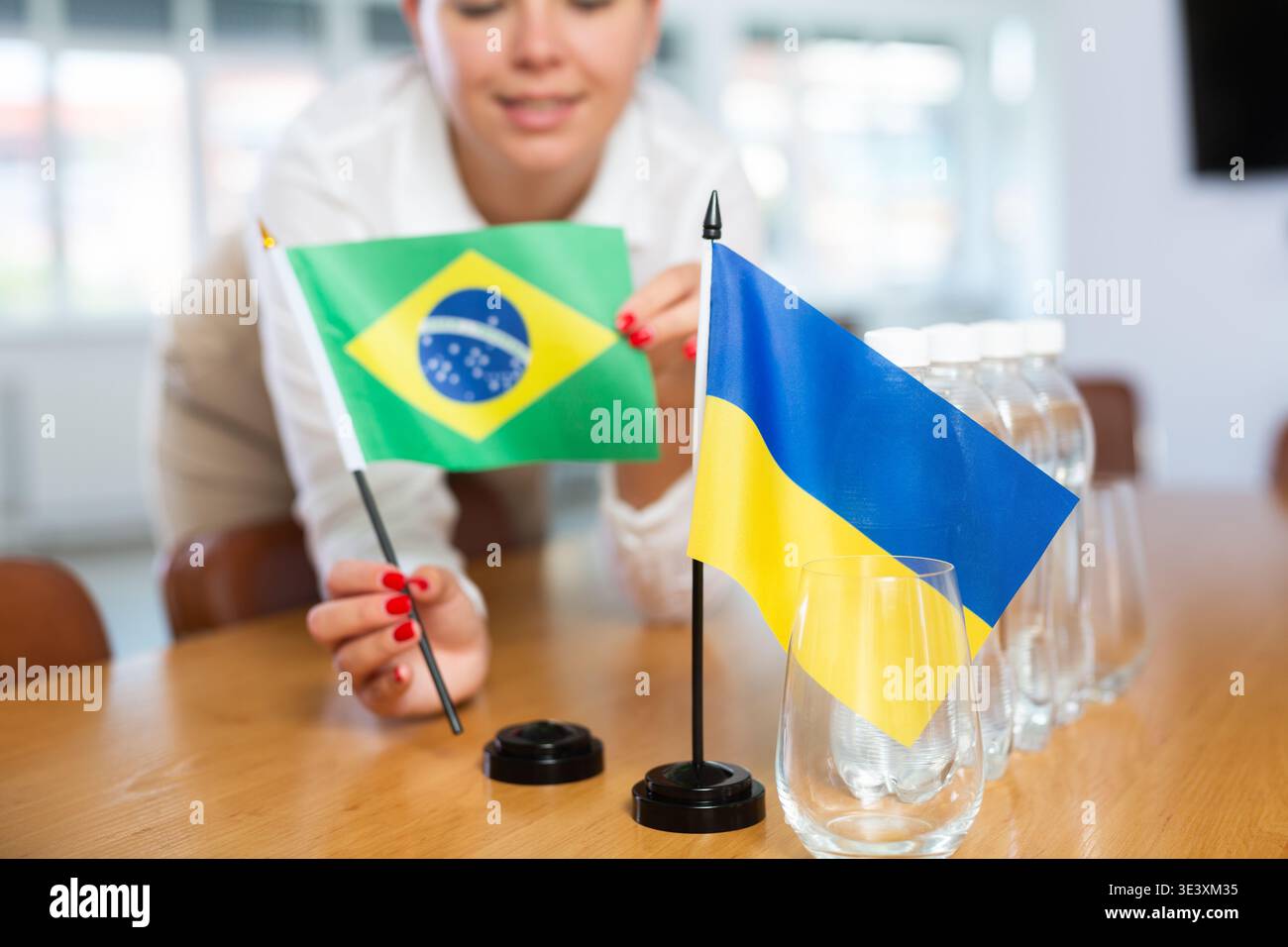 Drapeaux de table nationaux du Brésil et de l'Ukraine entre les mains d'une femme qui se prépare aux négociations Banque D'Images