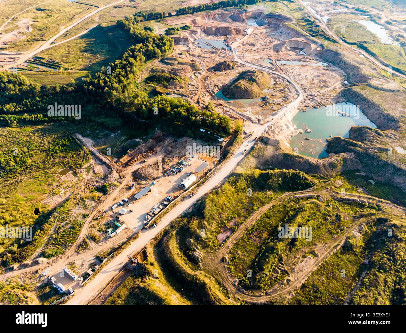 Vue aérienne d'une carrière active à ciel ouvert avec de multiples fosses excavées et piscines d'eau turquoise. Un chemin de terre serpente à travers le paysage industriel, Banque D'Images