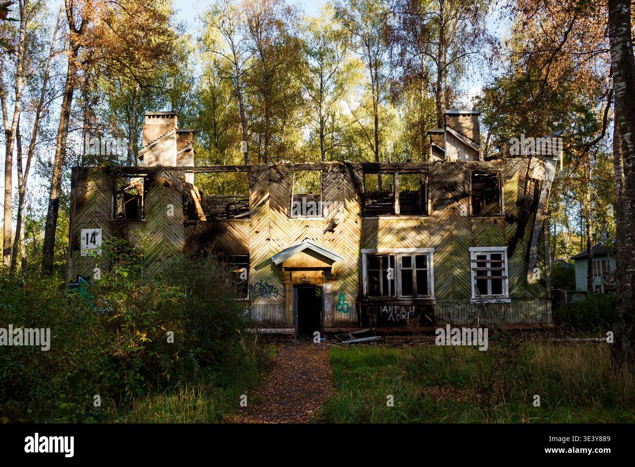Étrange maison en bois brûlée, un fantôme poignant de son passé, debout au milieu d'un feuillage d'automne vibrant, un sombre rappel de la décomposition et de la négligence Banque D'Images