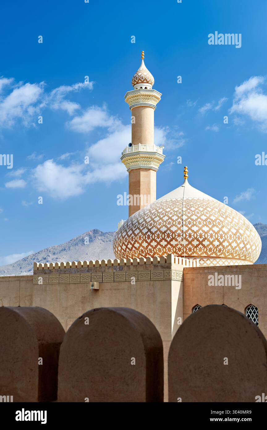Le fort de Nizwa à Oman dispose d'une tour de mosquée sous un ciel bleu avec des nuages. L'architecture met en valeur le design local et l'histoire. Banque D'Images