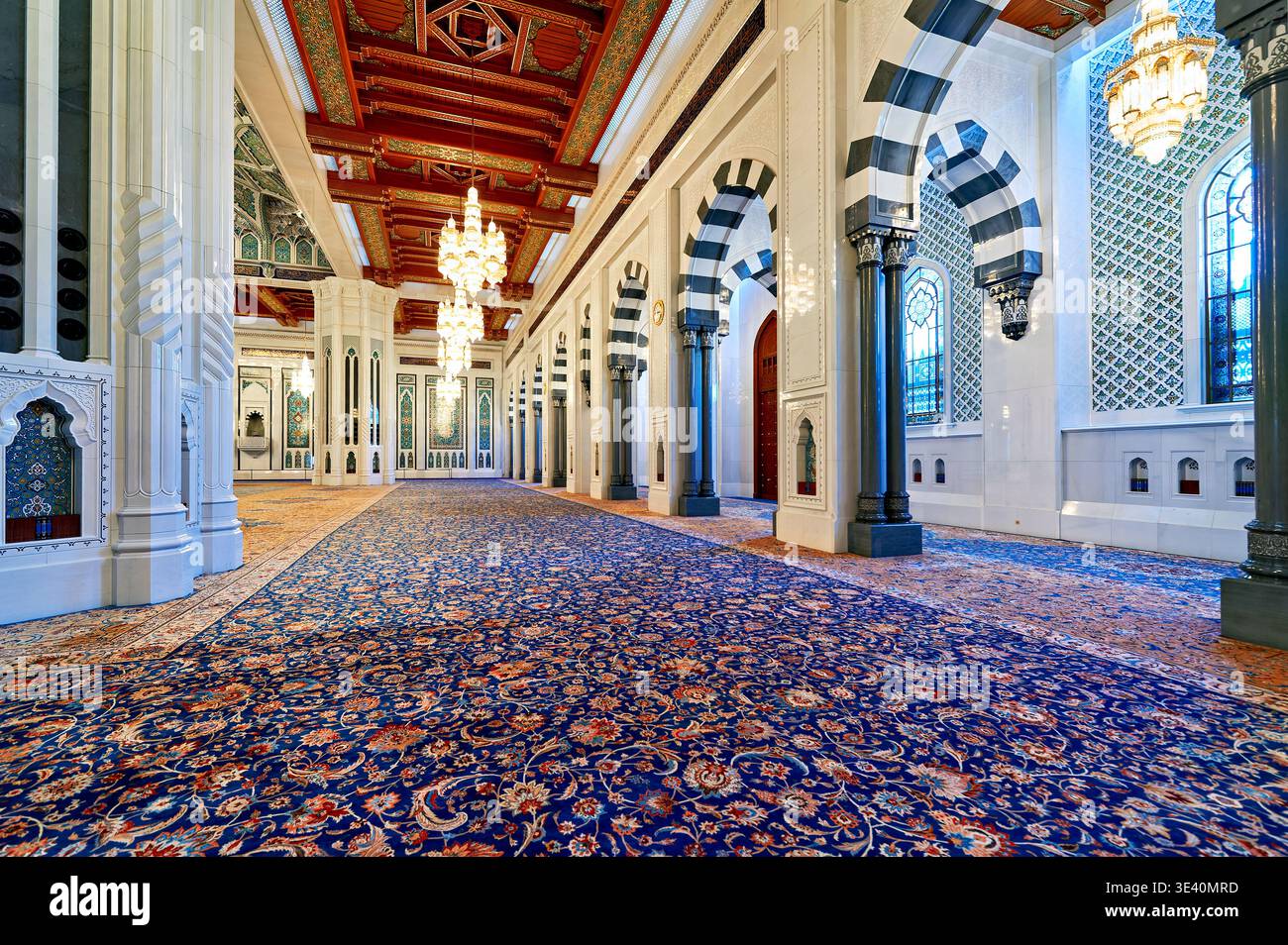 Les visiteurs se promènent dans la grande salle de la Grande Mosquée du Sultan Qaboos à Mascate. L'espace montre des conceptions et une architecture complexes. Banque D'Images