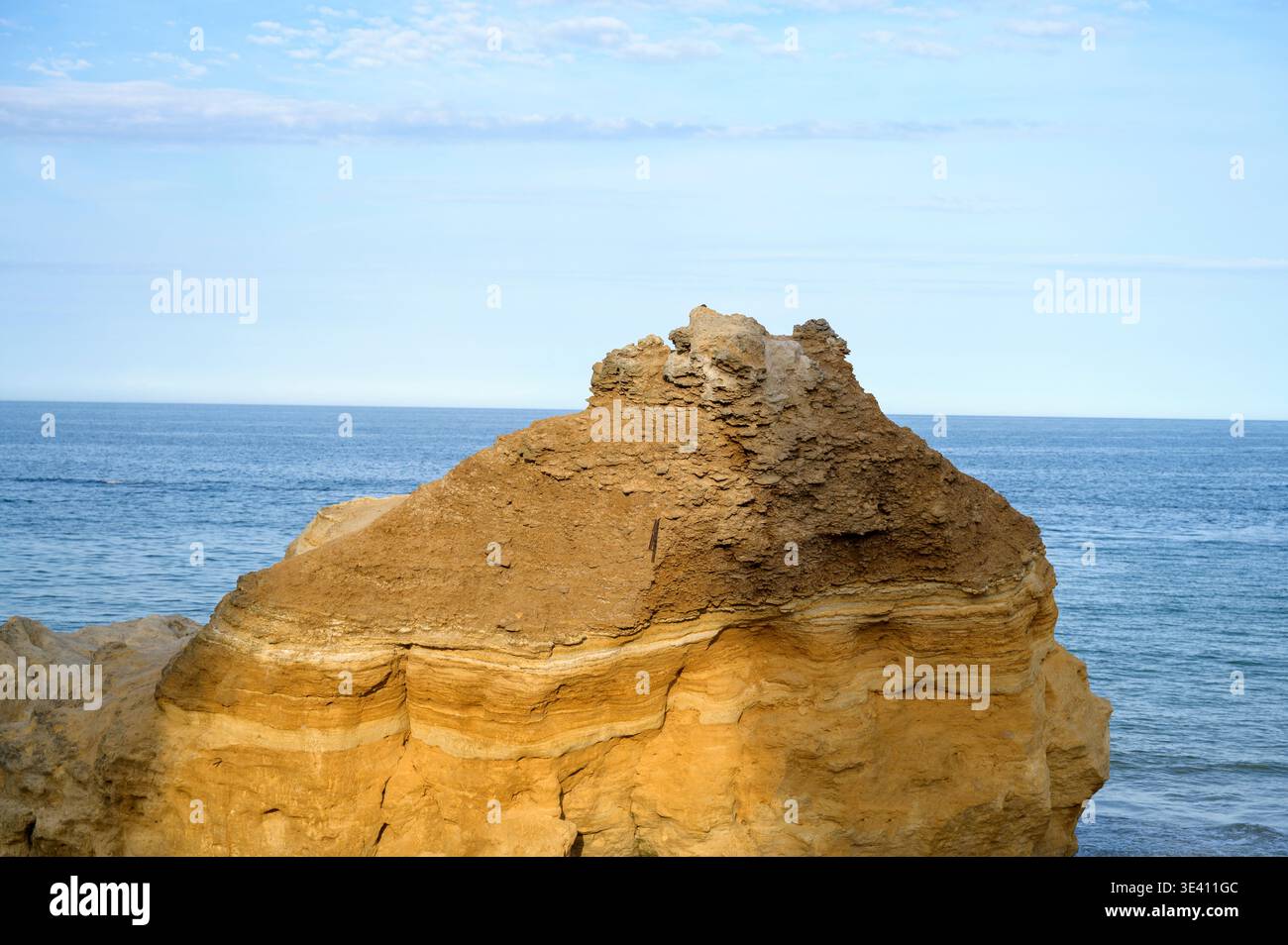 Falaise de grès jaune contre un ciel bleu vibrant et la mer. Lumière naturelle éclatante du soleil. Concept de patrimoine géologique, beauté côtière et pouvoir naturel Banque D'Images