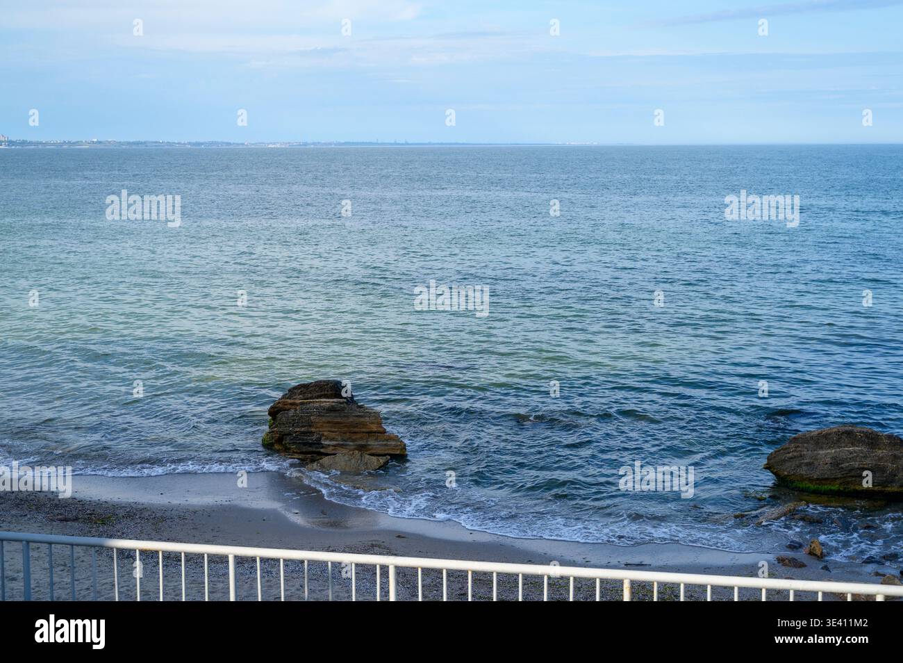 Surface de mer bleue calme avec des roches sombres dépassant de l'eau. Ligne d'horizon claire. Concept de beauté de la nature maritime, environnement côtier paisible, Banque D'Images