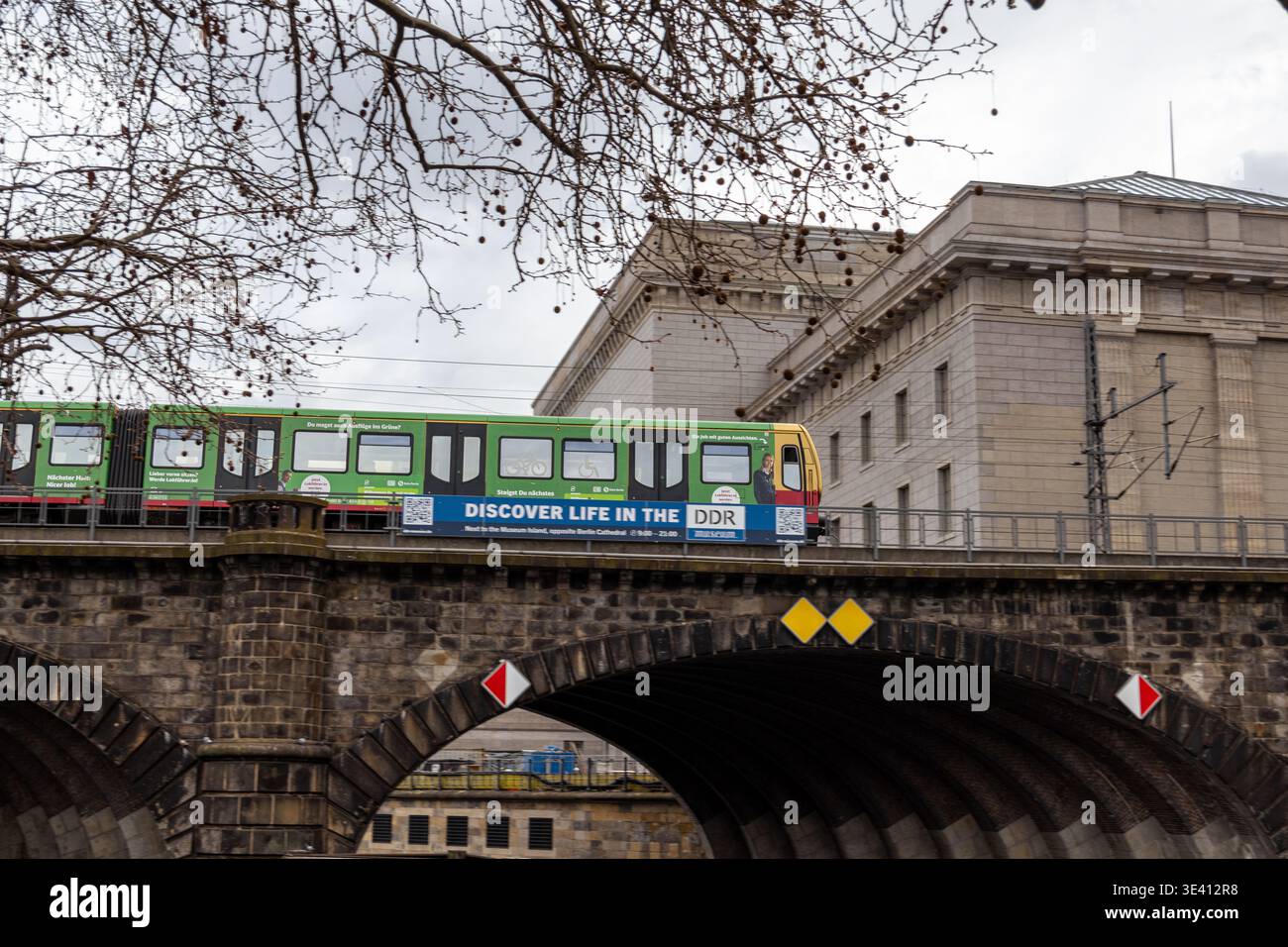 Une voiture de tramway passe sous un pont de pierre à Berlin, en Allemagne. Le pont a un design arqué distinctif avec des éléments décoratifs. Le tram est brillant Banque D'Images