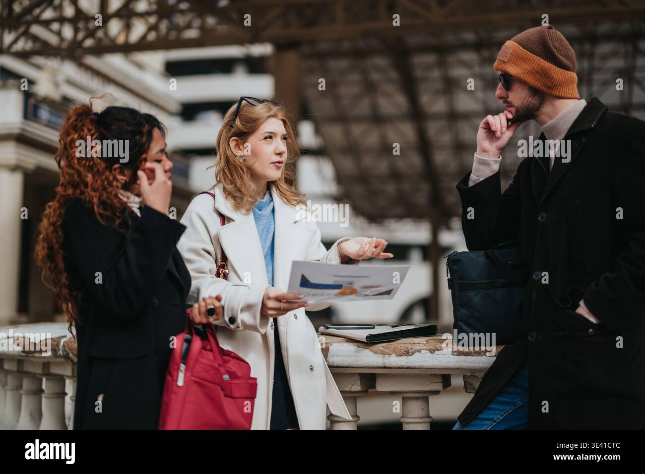Jeunes professionnels ayant une discussion d'affaires sur les documents de voyage à une station extérieure Banque D'Images