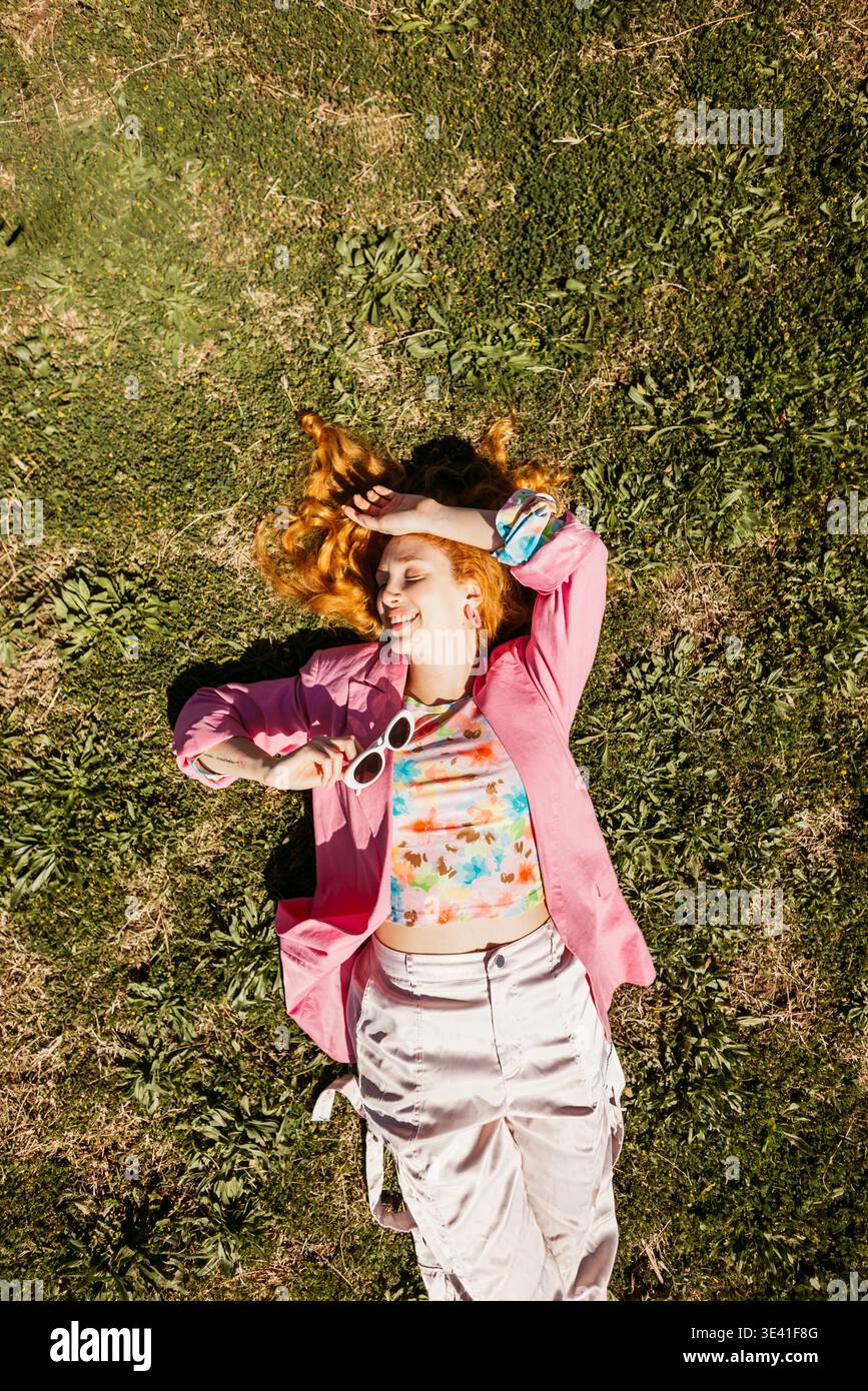 Jeune femme allongée sur l'herbe profitant des rayons du soleil pendant une journée paisible Banque D'Images