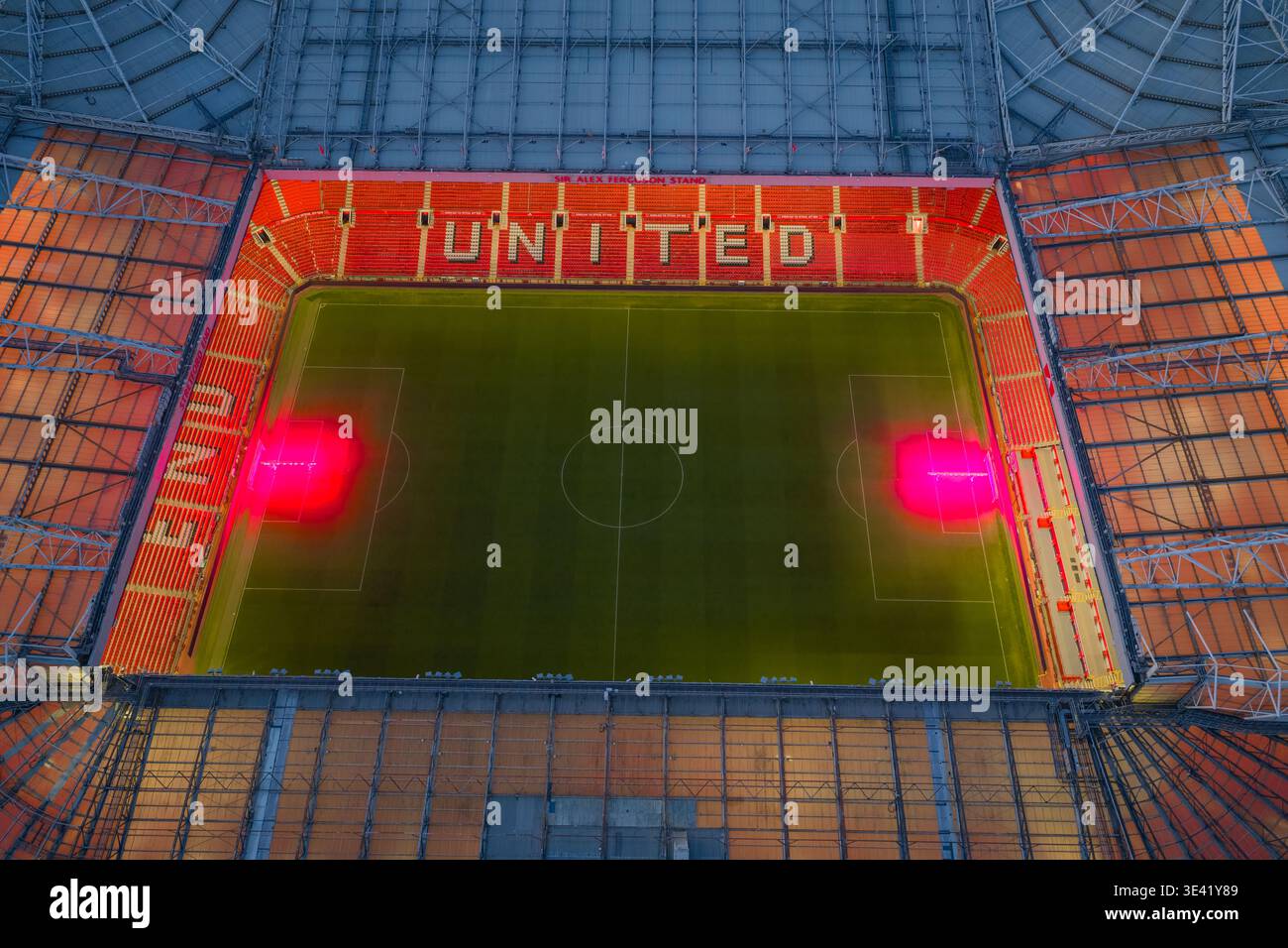 Image aérienne suspendue regardant vers le bas le terrain Old Trafford avec des lampes UV de culture et le lettrage « UNITED » dans les tribunes, Manchester, Royaume-Uni. Banque D'Images