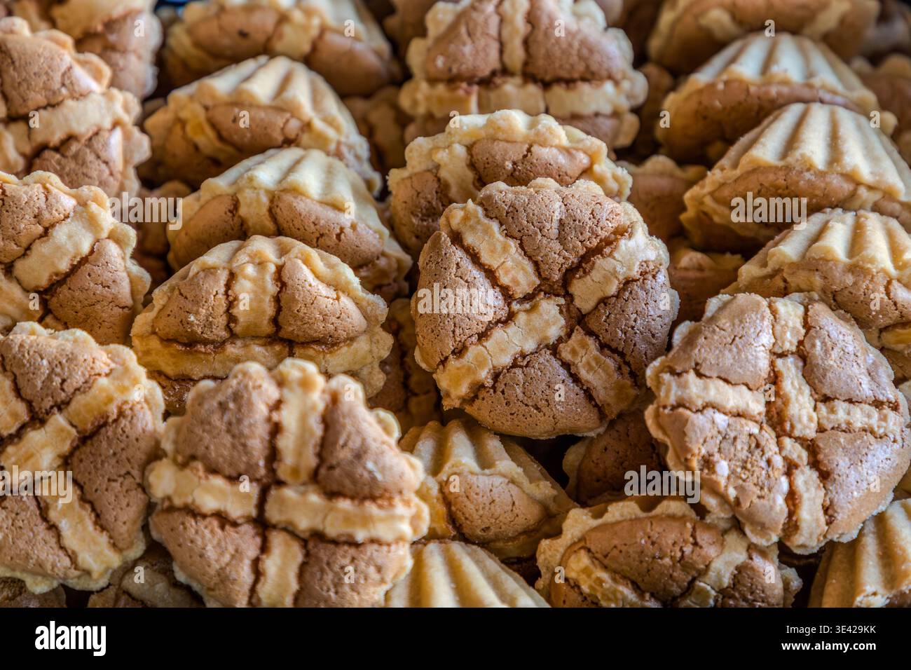 Un gros plan de Leipziger Lerchen (boules de sablés de massepain côtelées) dans une boulangerie : variétés claires et foncées empilées étroitement dans le présentoir. Leipzig, Saxe, Allemagne Banque D'Images