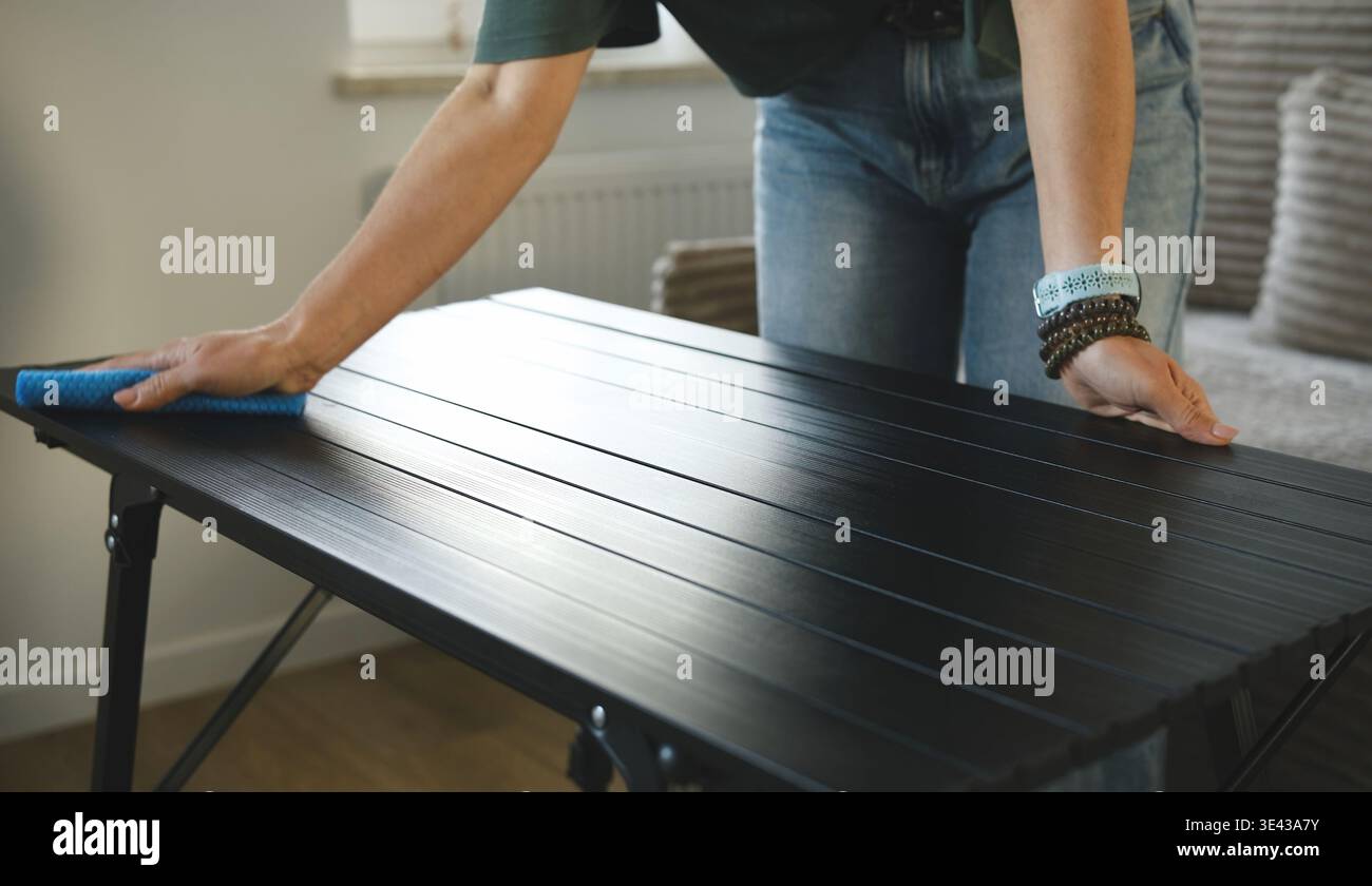 Fille polir la surface de la table avec Un chiffon dans le cadre de la routine de nettoyage de la pièce Banque D'Images