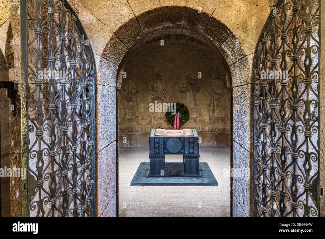 Vue intérieure du mausolée Quero à travers des portes en fer forgé. Il présente le sarcophage central en bronze et un mur avec des sculptures en relief de soldats. Banque D'Images