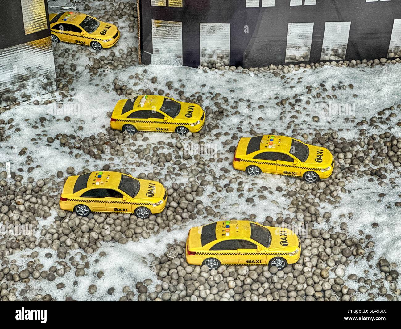 Une petite flotte de taxis jaunes jouets dans une vitrine naviguent dans une rue New-yorkaise remplie de fausse neige. Banque D'Images