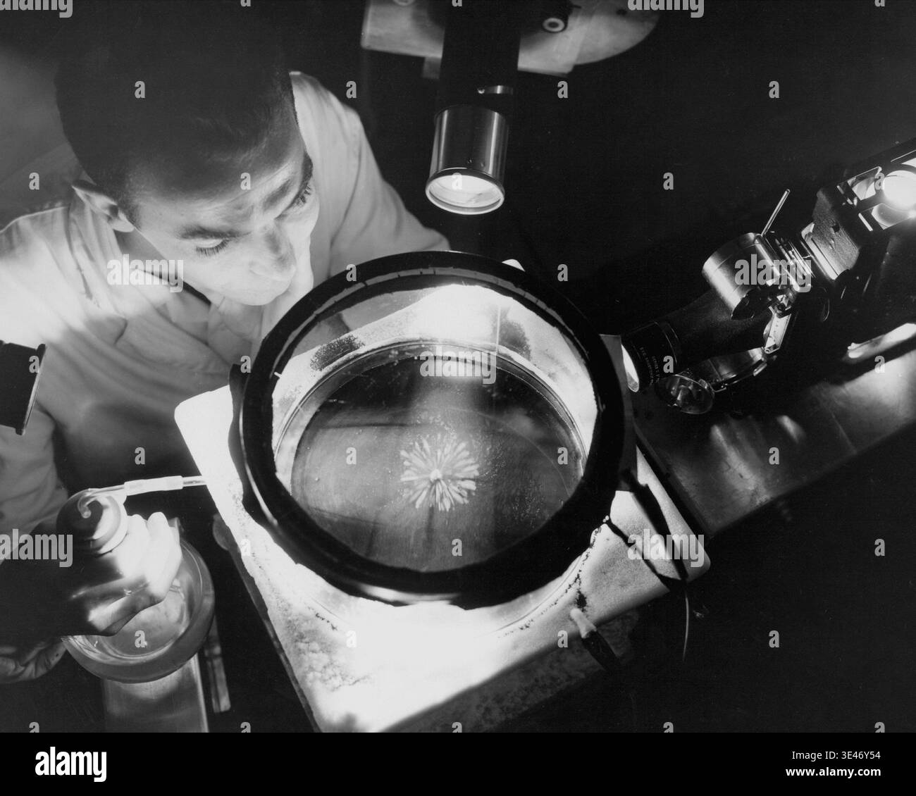 Le physicien de la NACA étudie les rayons alpha dans une chambre à nuages continus en 1957. La recherche visualise les traces de particules afin de minimiser les effets des rayonnements sur les composants des avions nucléaires. Banque D'Images