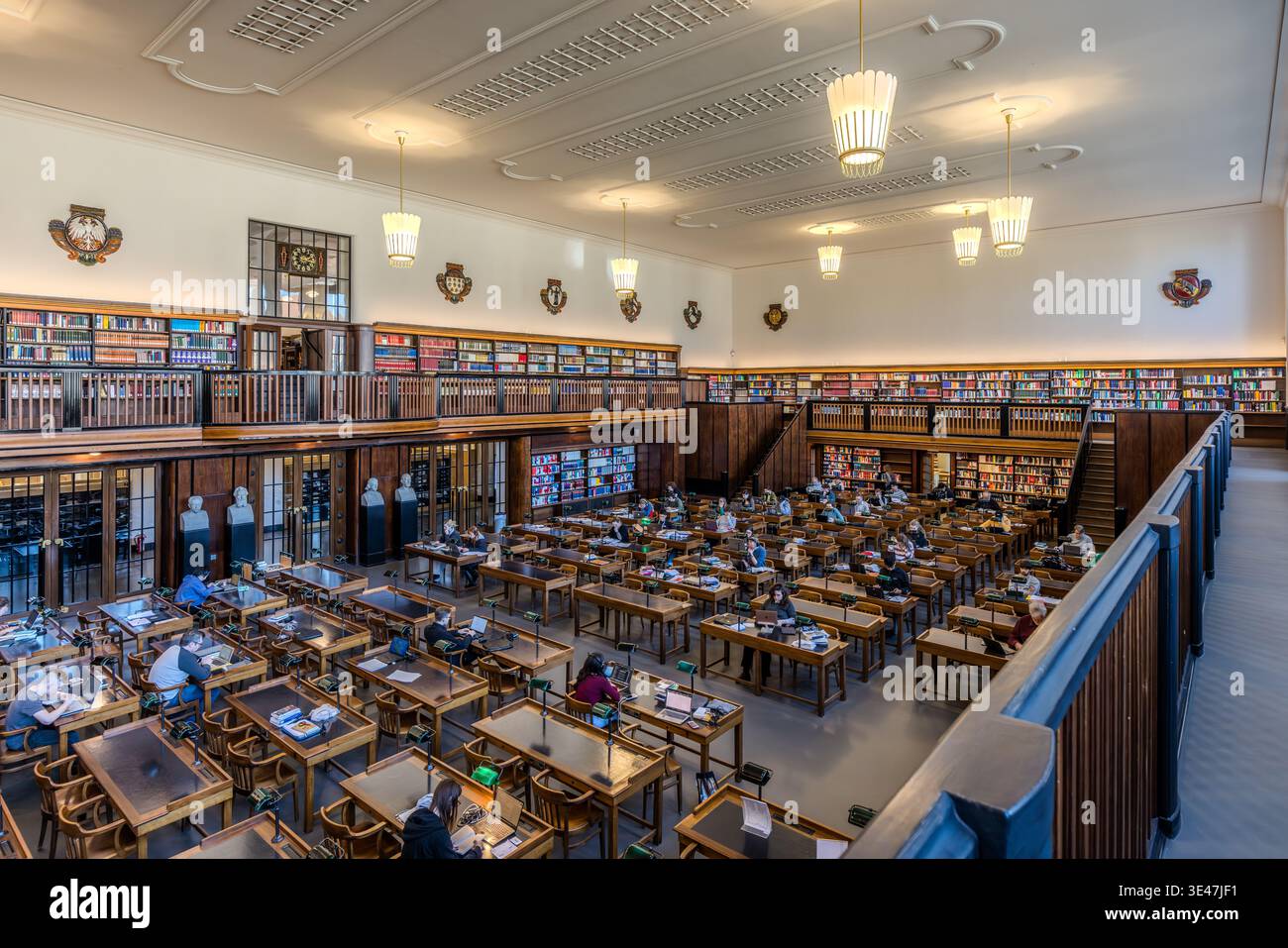 La première salle de lecture de la Bibliothèque nationale allemande de Leipzig, avec des lampes de lecture vertes et une surface de travail en linoléum vert. Les murs sont ornés de fresques représentant des motifs nazaréens tardifs. Leipzig, Saxe, Allemagne Banque D'Images