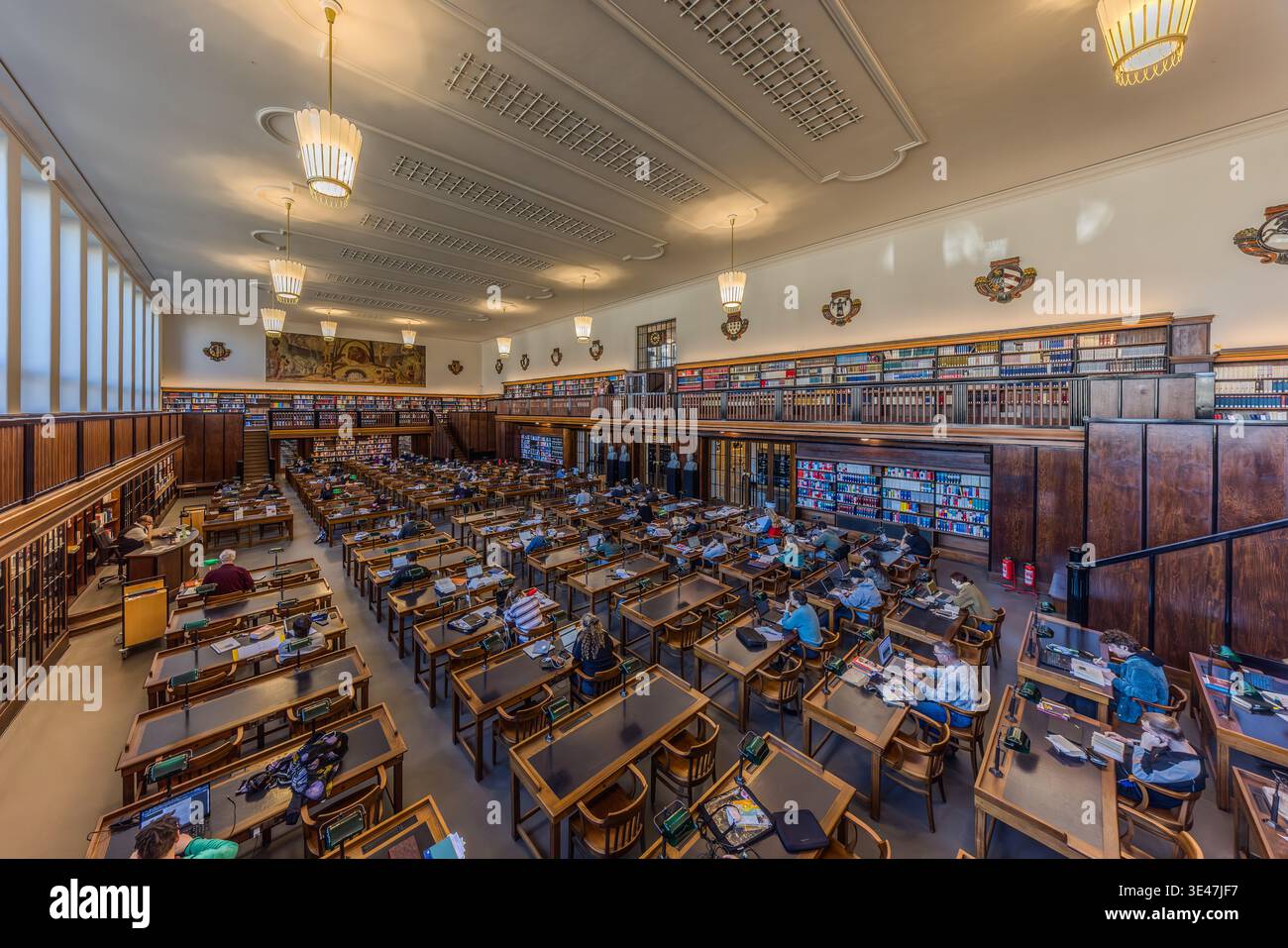 La première salle de lecture de la Bibliothèque nationale allemande de Leipzig, avec des lampes de lecture vertes et une surface de travail en linoléum vert. Les murs sont ornés de fresques représentant des motifs nazaréens tardifs. Leipzig, Saxe, Allemagne Banque D'Images