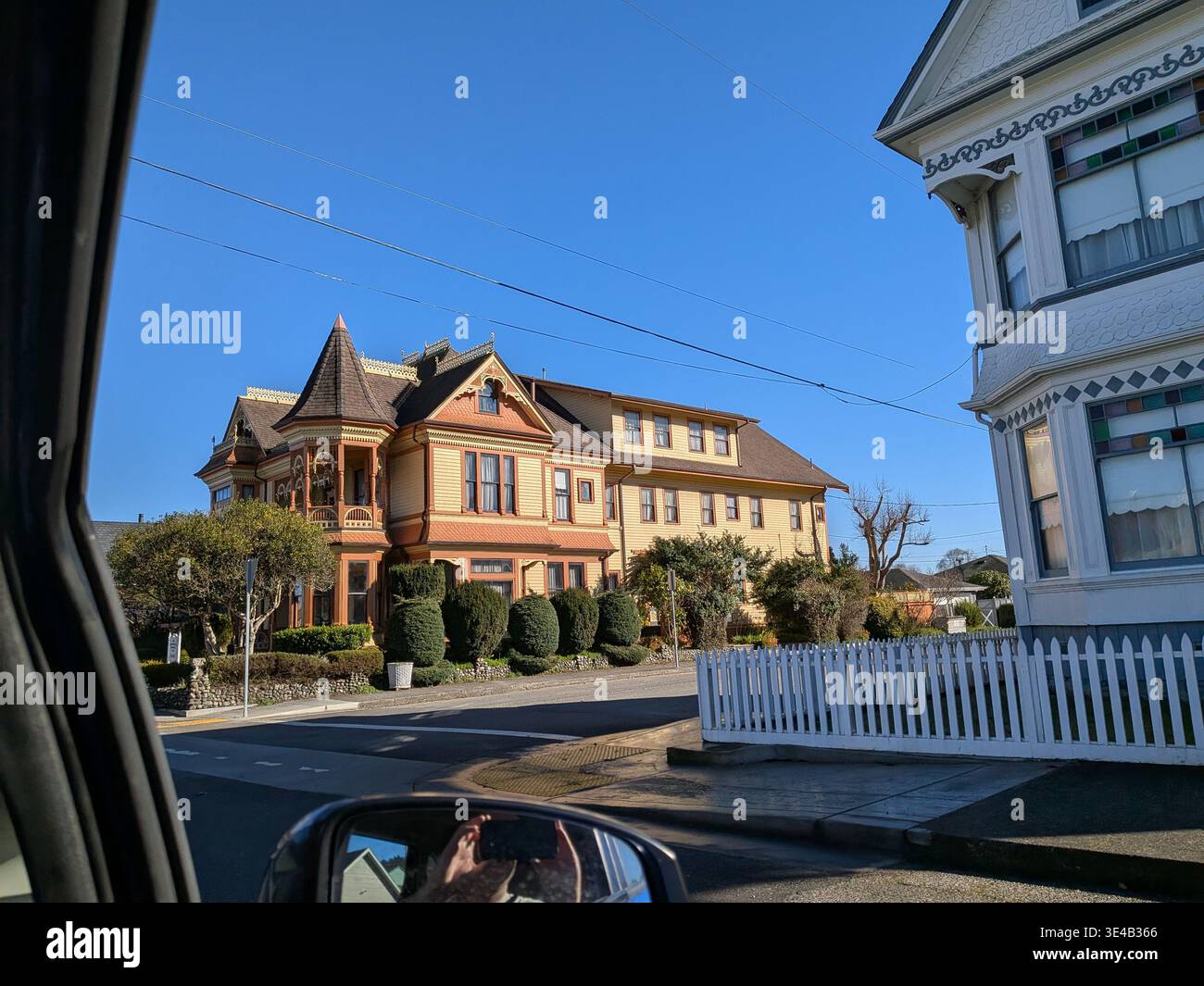 Orné orange victorien "Gingerbread Mansion" B & B avec des finitions complexes et un aménagement paysager luxuriant, capturant le charme de conte de fées et l'élégance historique sous le bleu - Image de stock capturée avec un smartphone