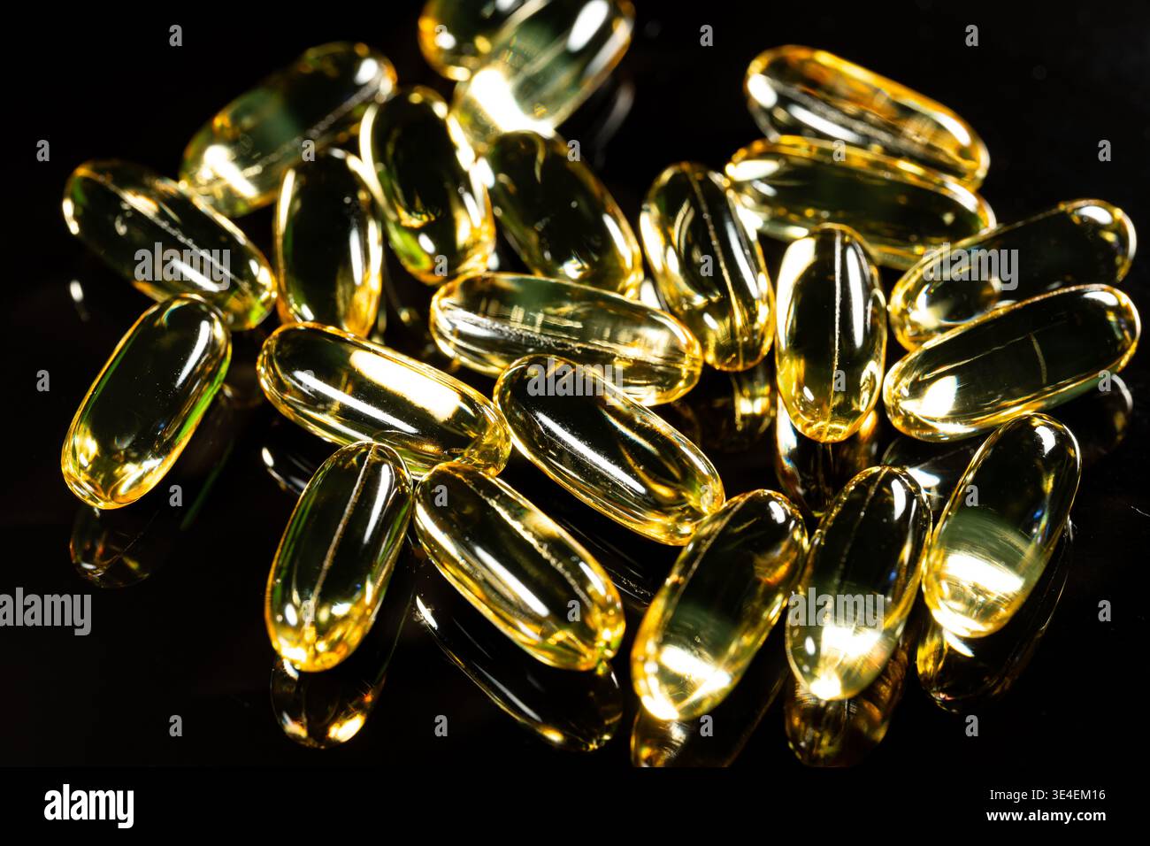 Capsules d'oméga 3 doré sur fond réfléchissant noir, macro gros plan de suppléments d'huile de poisson brillant pour une utilisation dans les soins de santé Banque D'Images