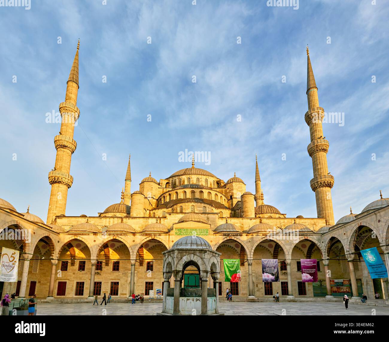 La Mosquée bleue est haute avec ses minarets alors que le soleil se couche à Istanbul. Les visiteurs se promènent et admirent l'architecture. Banque D'Images