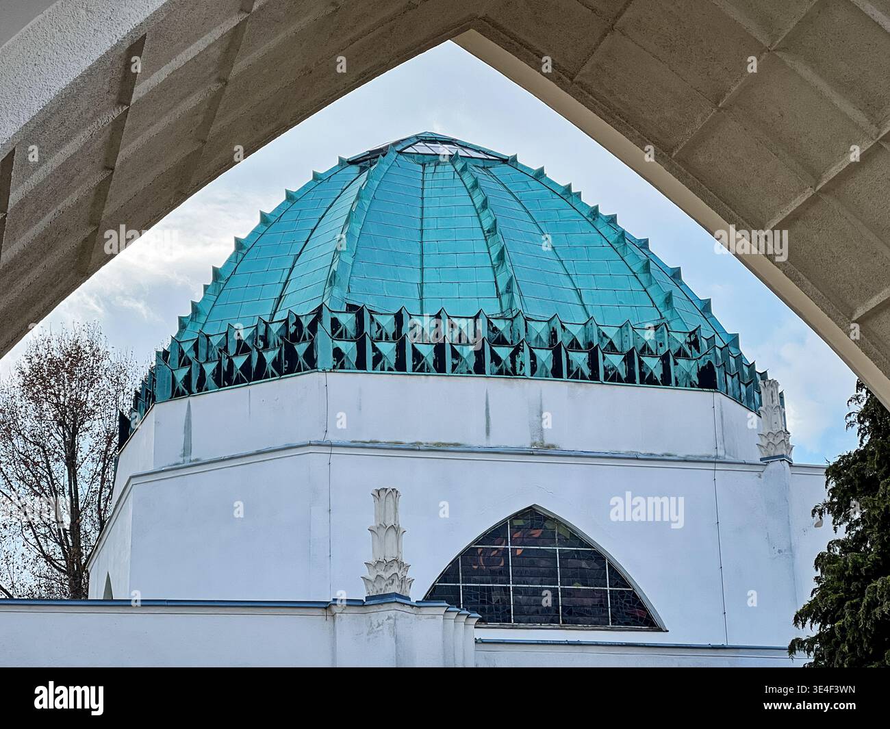 Un toit en cuivre altéré se trouve au sommet de la synagogue du cimetière central de Vienne, vu à travers une arche de pierre. Banque D'Images