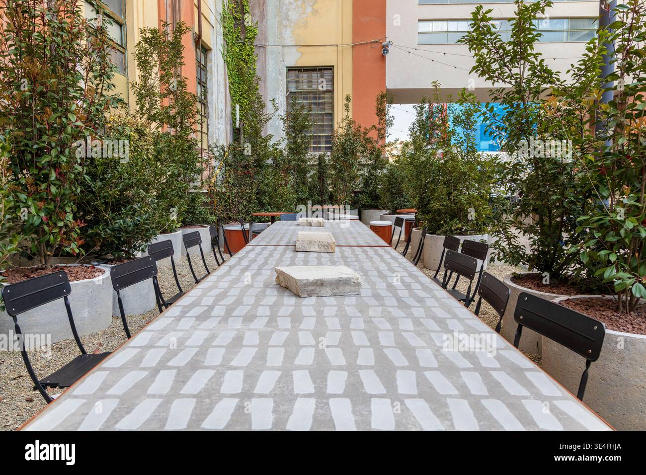 Table commune extérieure avec chaises noires dans la cour de Manifattura Tabacchi, Florence, Italie Banque D'Images