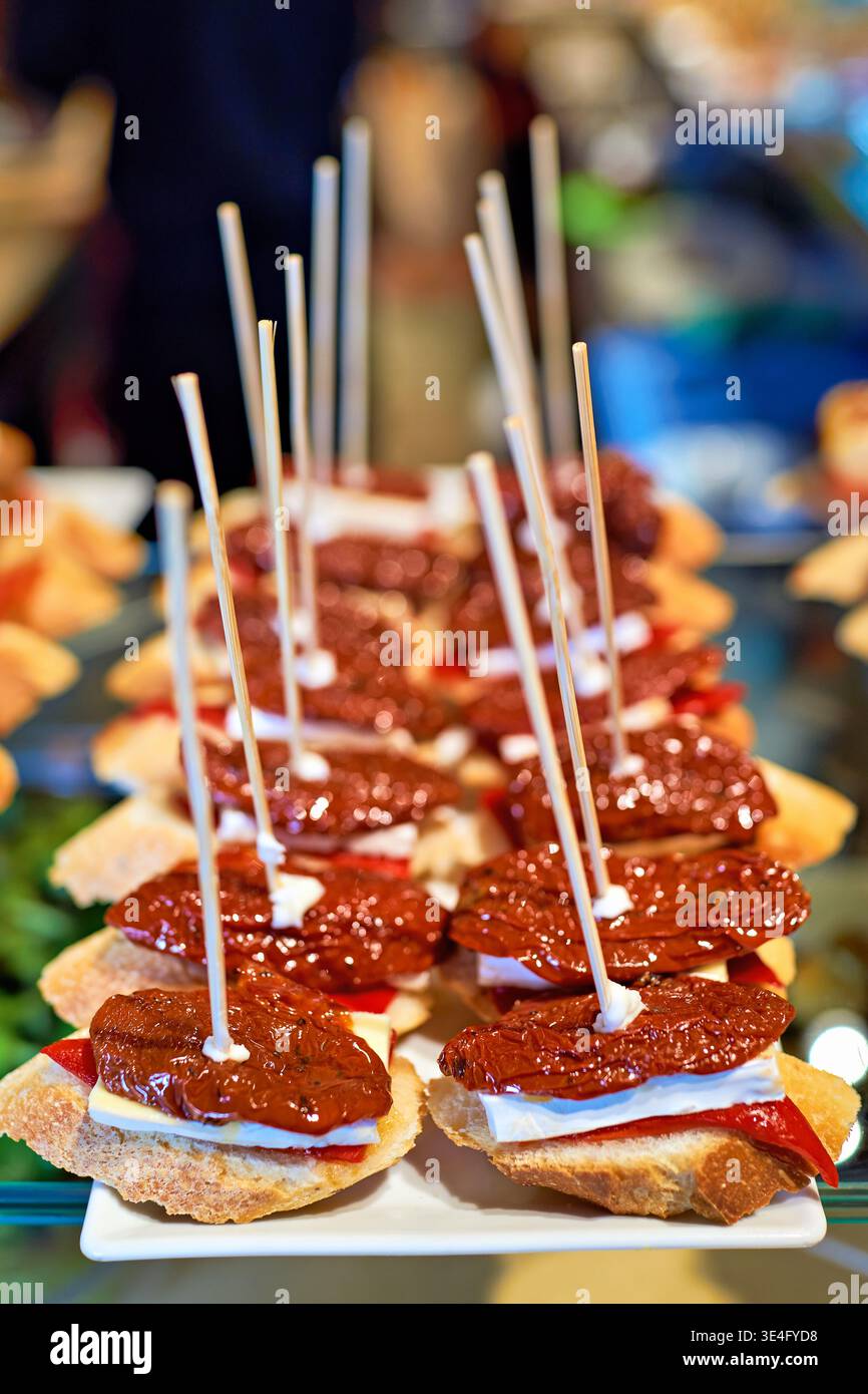 Les visiteurs du bar savourent une variété de tapas avec du pain et des garnitures à Barcelone. Les collations sont présentées sur des brochettes pour manger facilement pendant les moments décontractés. Banque D'Images