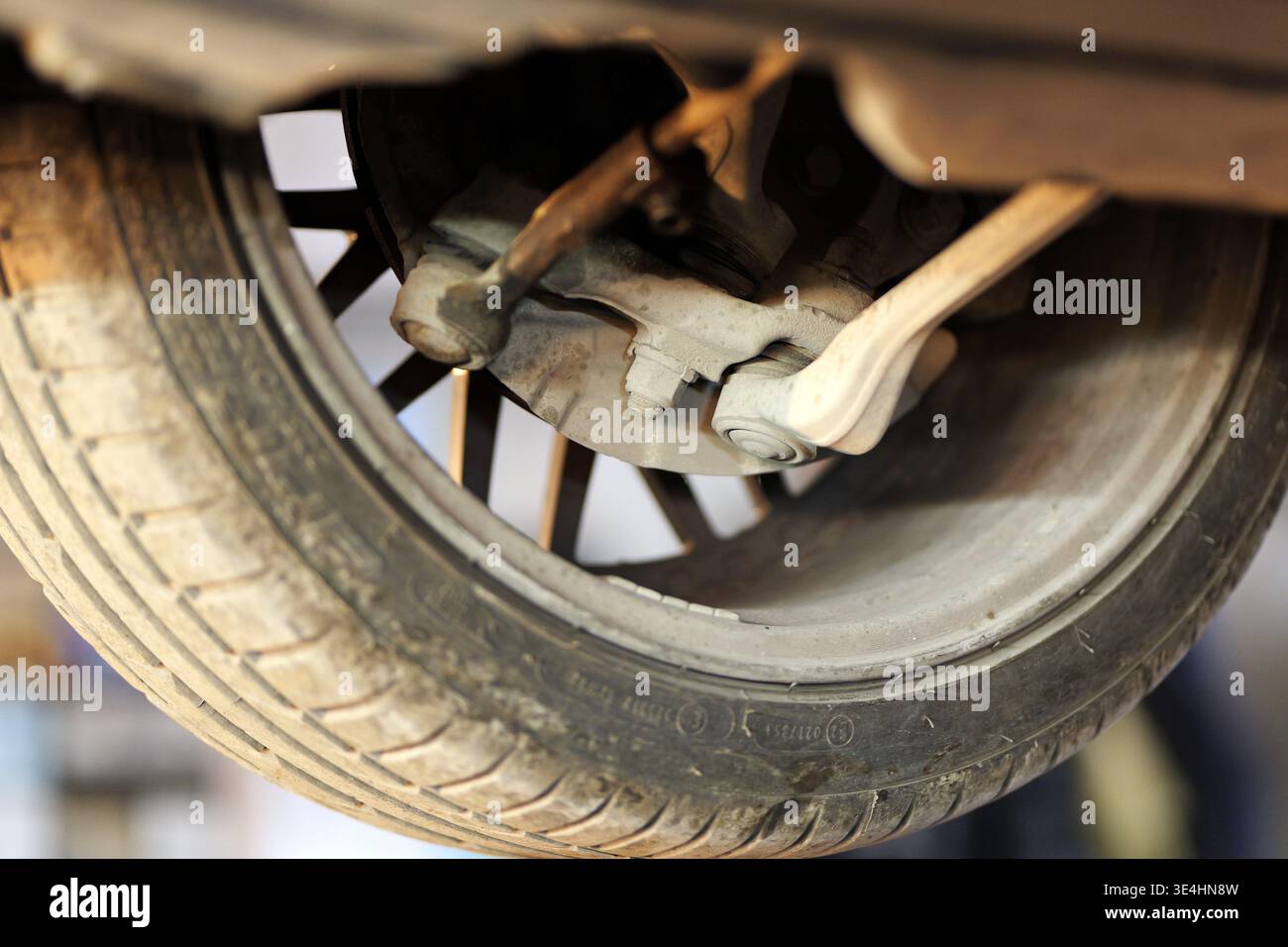 Un gros plan d'un système de suspension et de freinage d'une voiture montre la roue, le bras de suspension, la biellette de direction et le disque de frein par en-dessous sur un pont élévateur, 2026 Banque D'Images