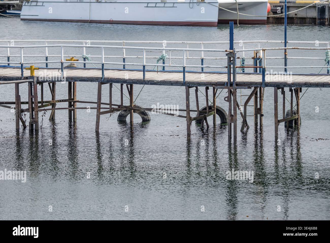 Poste d'amarrage en métal rugueux et son reflet dans l'eau du port au canal Beagle, tourné dans une lumière nuageuse d'été à Ushuaia, Argentine Banque D'Images