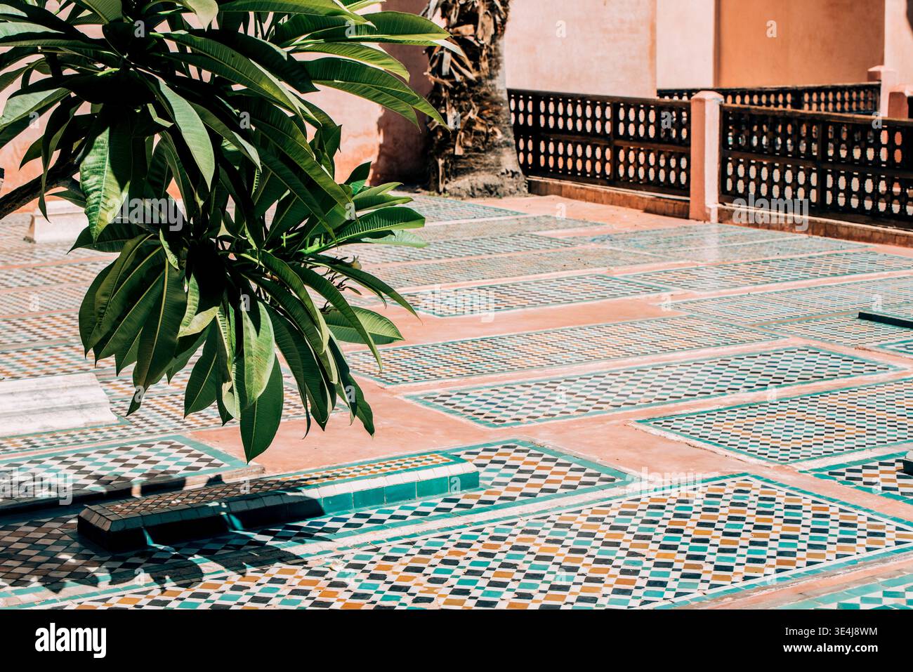 Cette cour marocaine ensoleillée est décorée de mosaïques colorées, de motifs géométriques et de murs en stuc chaleureux, mêlant architecture islamique traditionnelle Banque D'Images