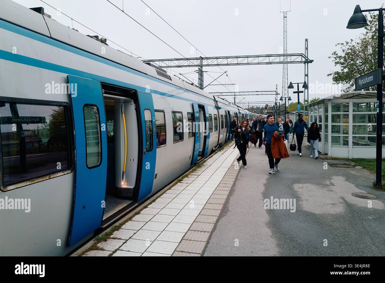 Un train de banlieue avec des gens qui en sortent. Le train est bleu et blanc. Nynashamn, comté de Stockholm, Suède, 9 mai 2025. Banque D'Images