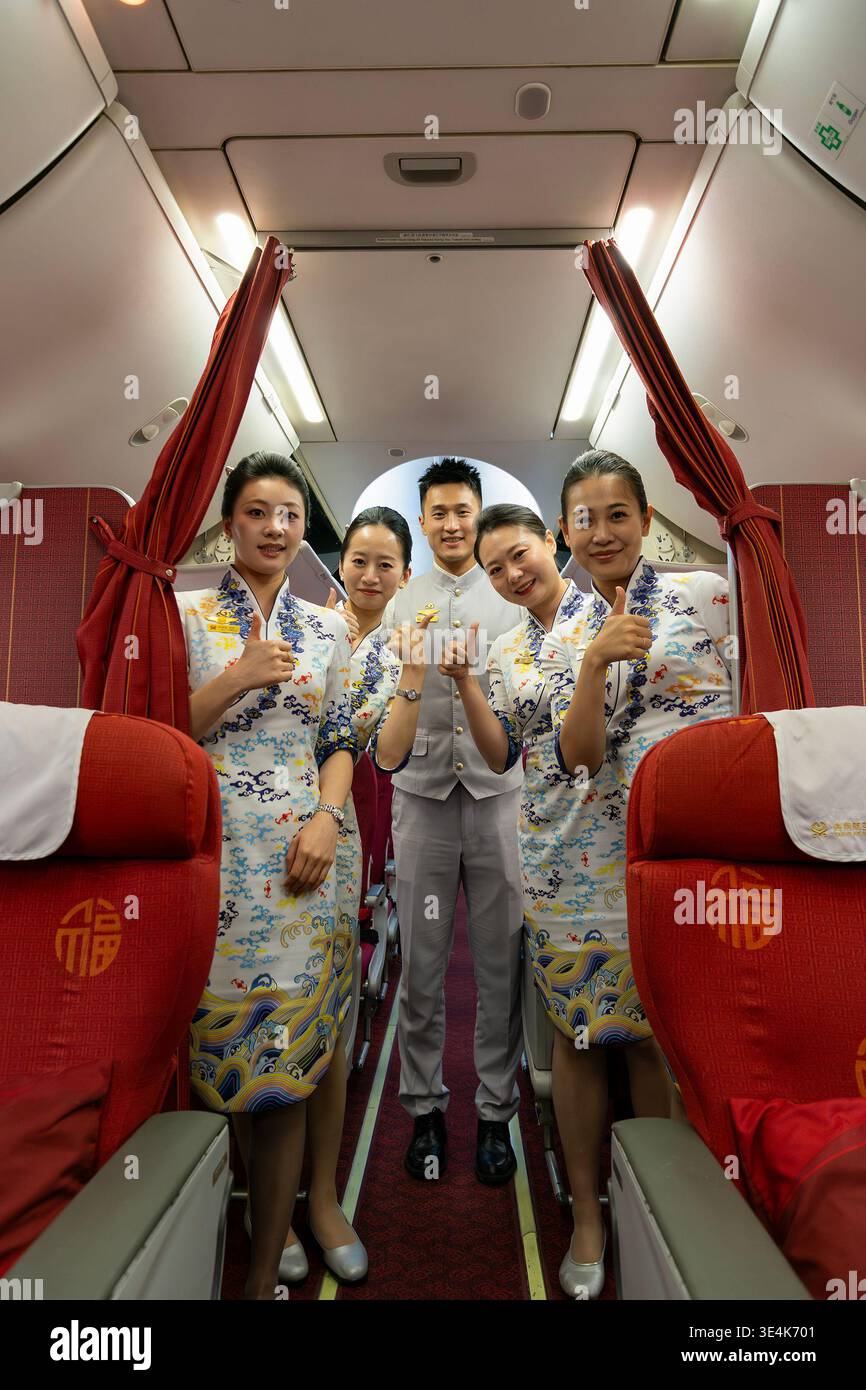 Singapour - 7 décembre 2025 : portrait de groupe complet de l'équipage de cabine de Hainan Airlines, des agents de bord et un steward masculin, debout et posant Banque D'Images