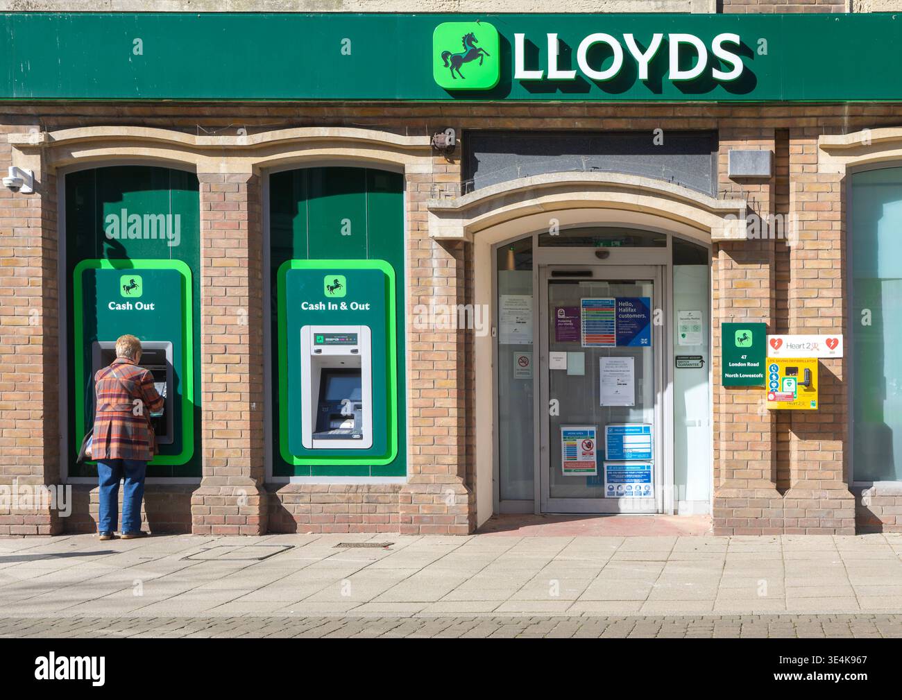 Personne utilisant un distributeur automatique de billets à la succursale de Lloyds Bank, centre-ville de Lowestoft, Suffolk, Angleterre, Royaume-Uni Banque D'Images