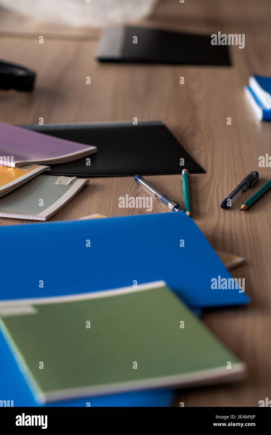 Une collection organisée de cahiers et d'articles de papeterie colorés sur une surface de table en bois Banque D'Images