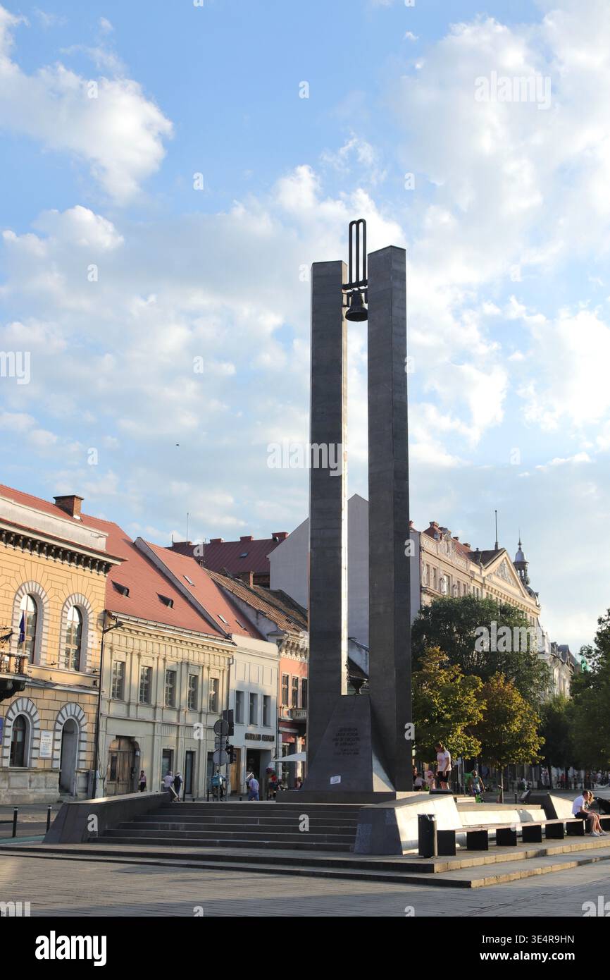 Cluj-Napoca, Roumanie - 12 août 2025 : Mémorial de la Révolution de 1989 avec le clocher Banque D'Images