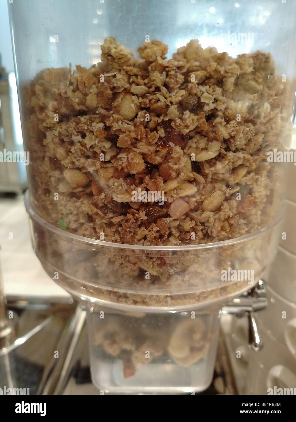 Distributeur de granola rempli d'ingrédients de granola mélangés, y compris l'avoine, les noix et les graines, placé dans un cadre de style buffet pour les options de petit-déjeuner Banque D'Images