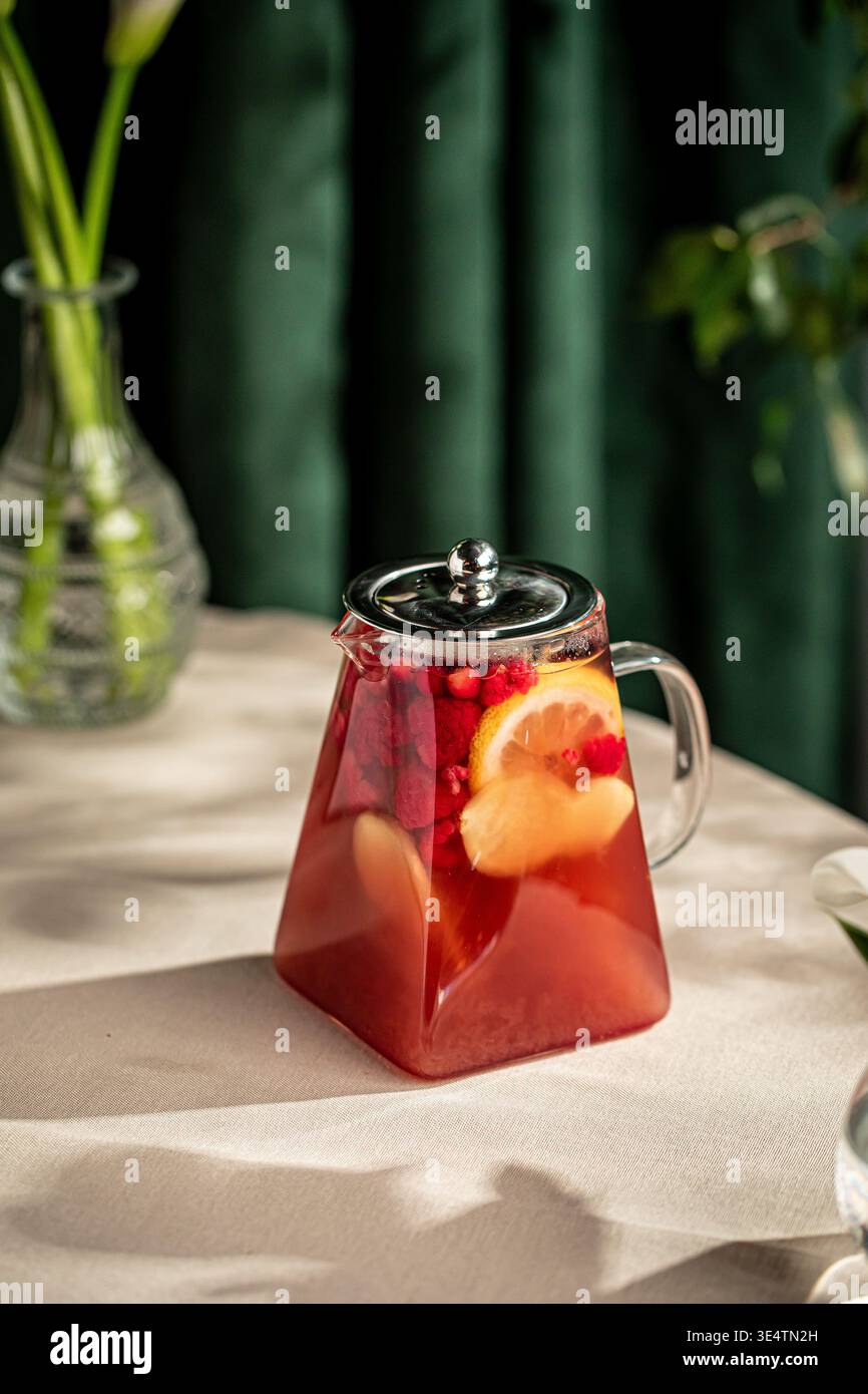 Thé aux fruits avec des baies d'agrumes dans une théière en verre Banque D'Images