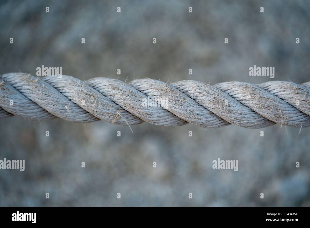 Une photographie horizontale détaillée capture le motif complexe d'un cordon de chanvre lourd avec des fibres effilochées sur un fond flou. Banque D'Images