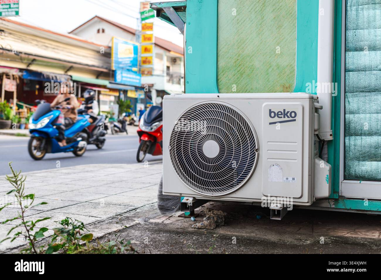 Ko Samui, Thaïlande, 20 mars 2026 : climatiseur monté sur un petit kiosque de rue avec des scooters de passage Banque D'Images