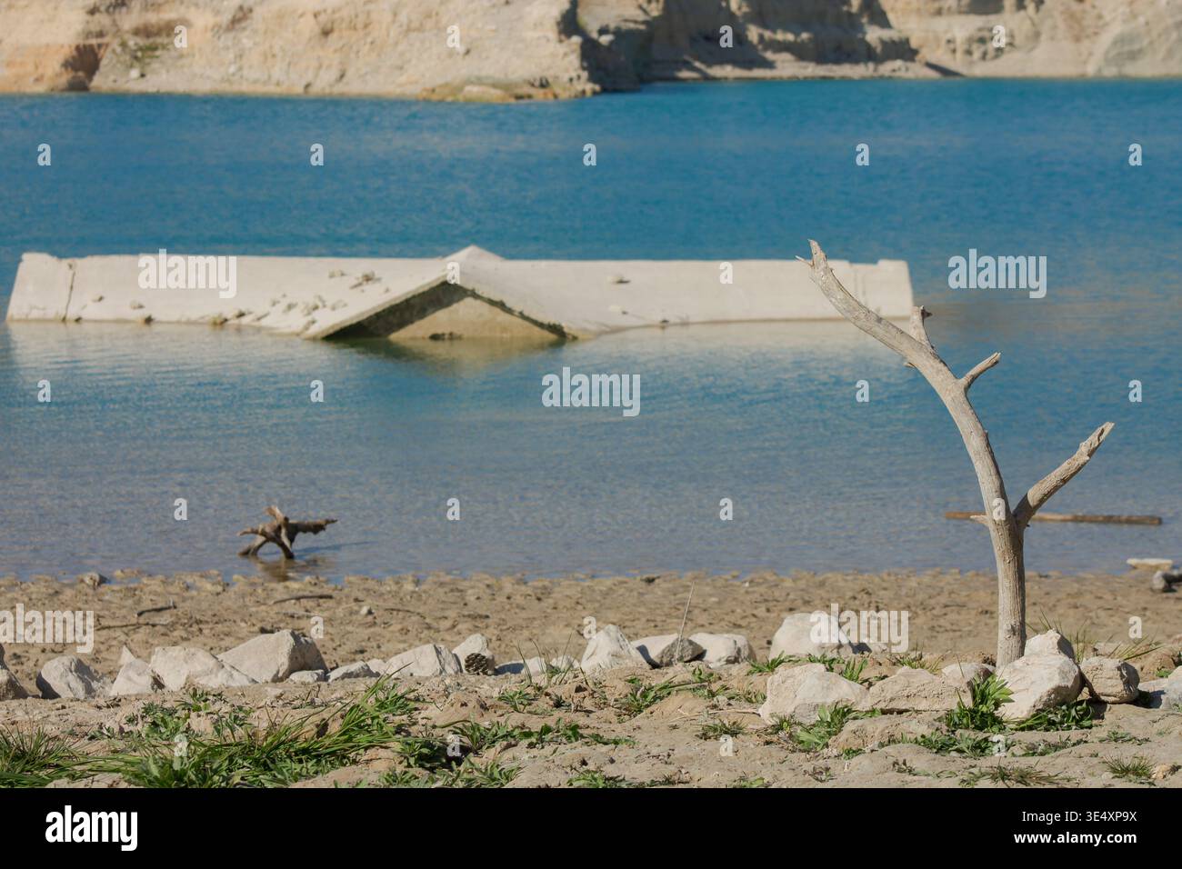 Une image frappante d'une branche morte debout sur le rivage sec du réservoir Amadorio à Alicante. Espagne. En arrière-plan. l'étoile emblématique en forme de c Banque D'Images