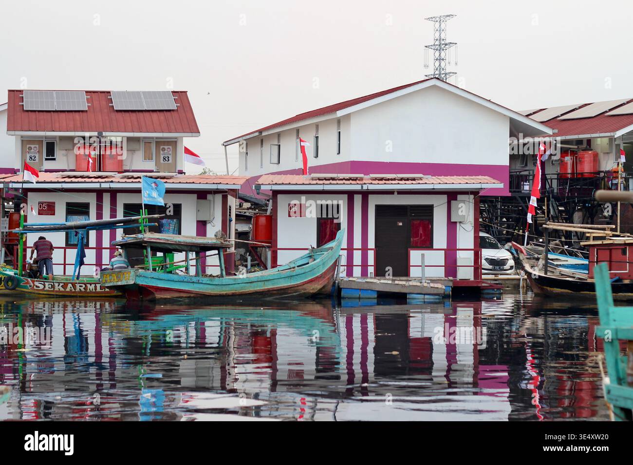 Maisons flottantes colorées et petits bateaux bordent le front de mer calme à Muara Angke, Jakarta, Indonésie, adaptation côtière aux inondations. Banque D'Images